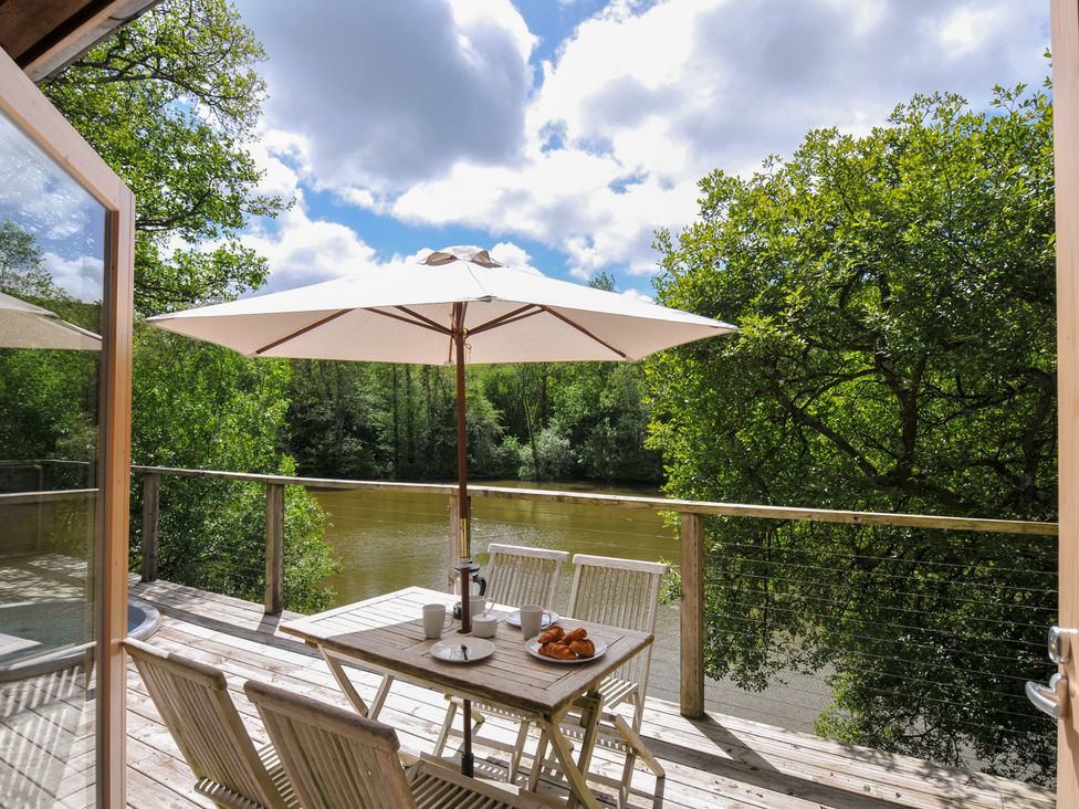 An outdoor seating area with table and chairs near a river at 11 Water's Edge near Pelynt