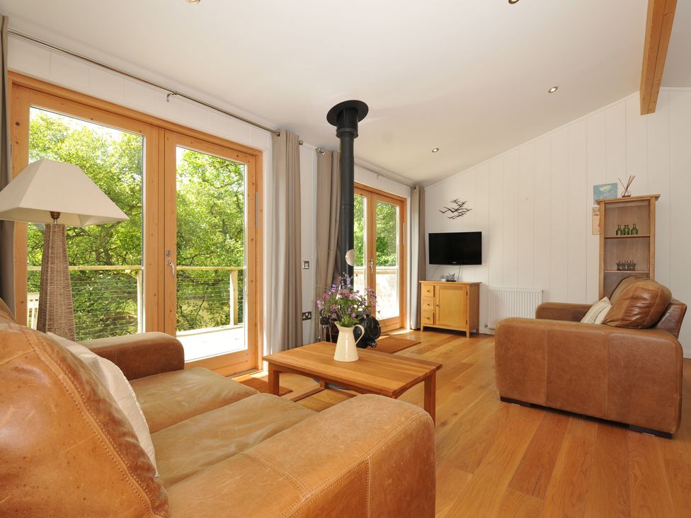 A living room with a sofa, coffee table, and television at 11 Water's Edge near Pelynt