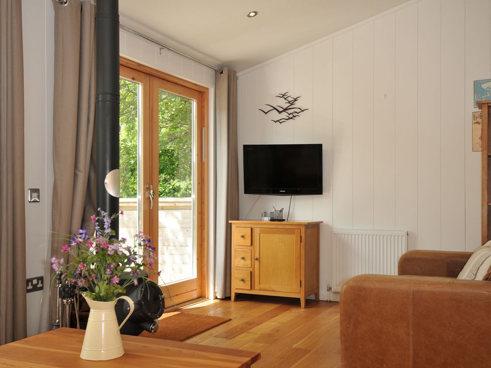 A living room with a television and wooden cabinet at 11 Water's Edge near Pelynt