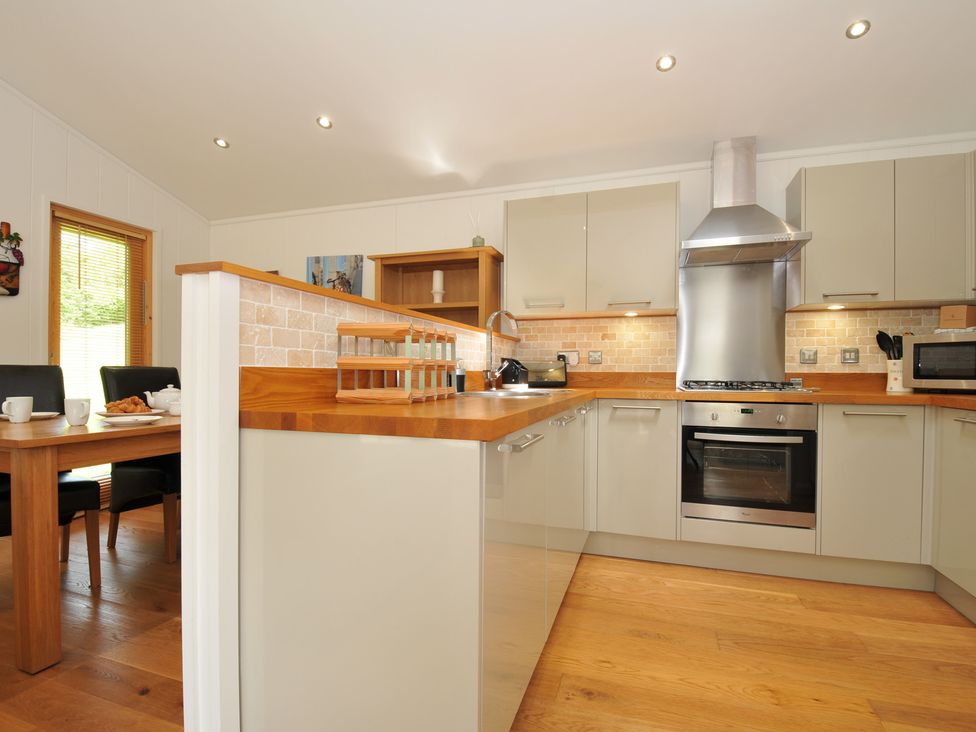 A kitchen with cabinets and a dining table at 11 Water's Edge near Pelynt