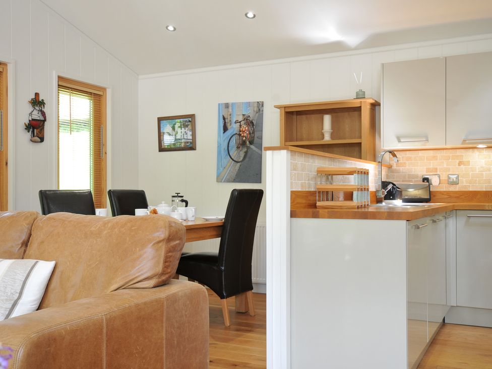 A kitchen with a dining table and seating at 11 Water's Edge near Pelynt
