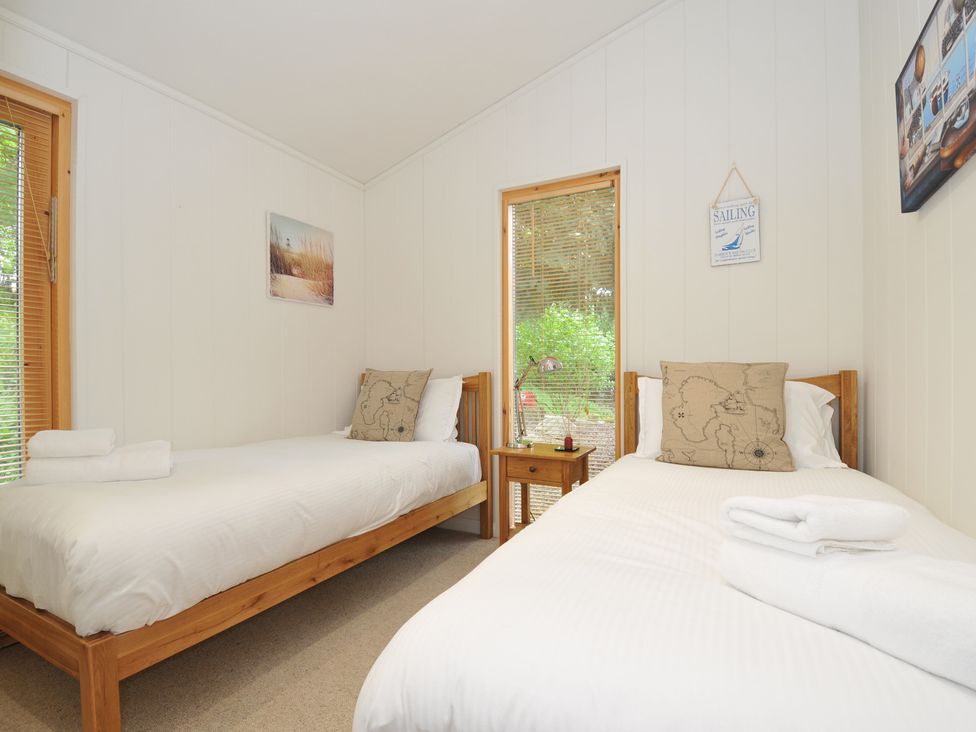 A bedroom with two beds and a nightstand at 11 Water's Edge near Pelynt
