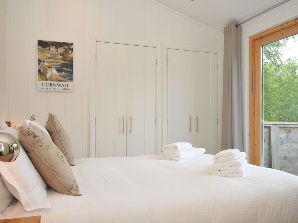 A bedroom with a bed and wardrobe at 11 Water's Edge near Pelynt