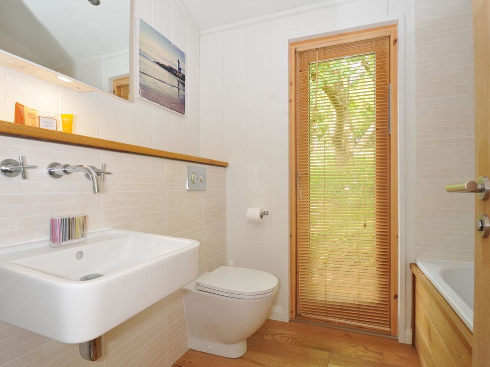 A bathroom featuring a sink, toilet, and window at 11 Water's Edge near Pelynt