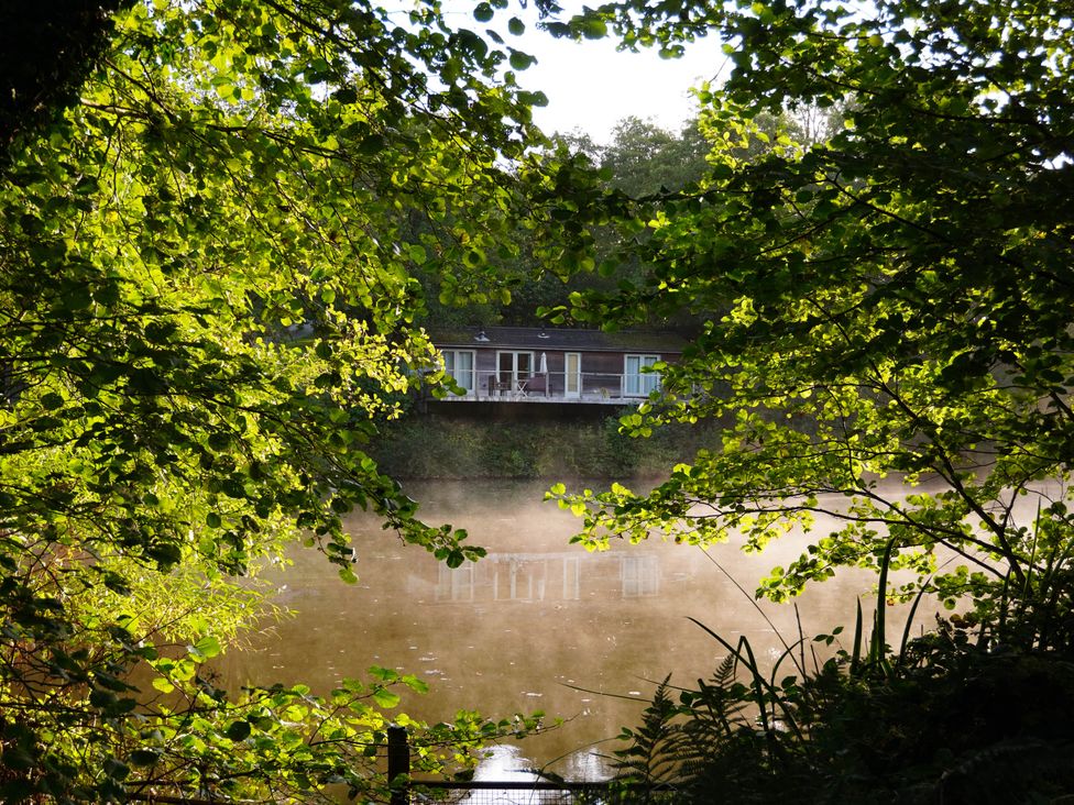 A house by the water surrounded by trees at 11 Water's Edge in Lanreath