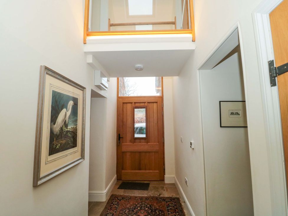 An entrance hallway with a wooden door and artwork at Tuxwell Lodge in Bridgwater
