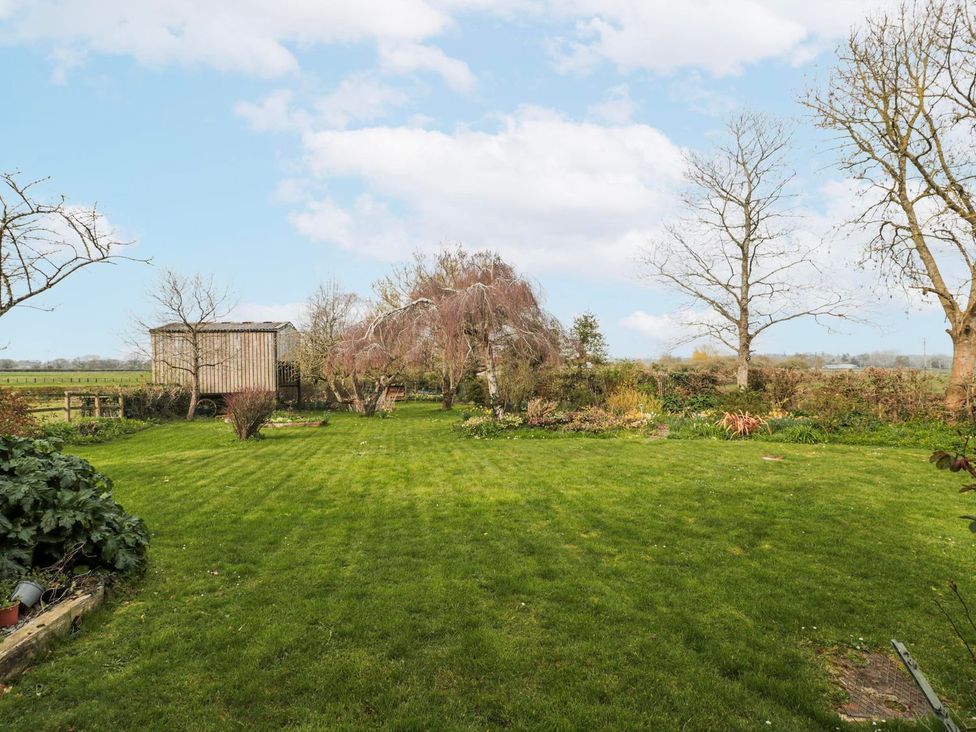 A garden with grass and a wooden shed at Tuxwell Lodge in Bridgwater