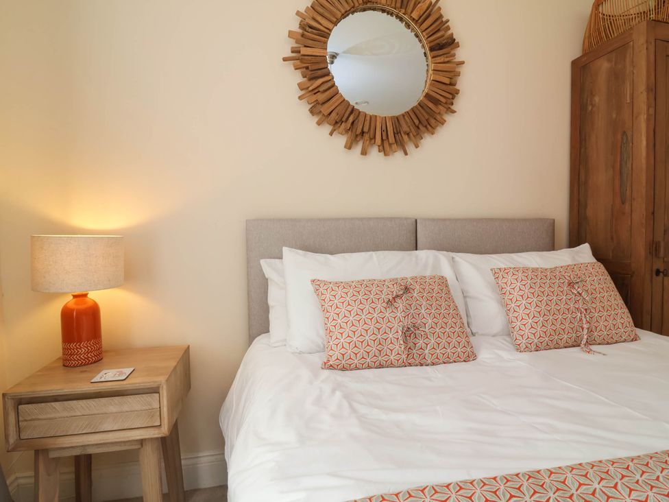 A bedroom with a bed, nightstand, and mirror at Sea Vista in Westward Ho!