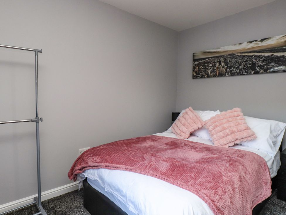 A bedroom with a bed and clothes rack at Ger y Mynydd, 2 Cae Ty Coch, Brynteg