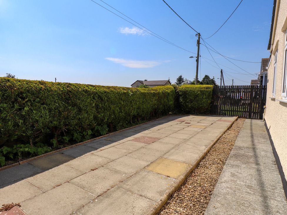An outdoor area with paving stones and a hedge at Ger y Mynydd, 2 Cae Ty Coch in Brynteg