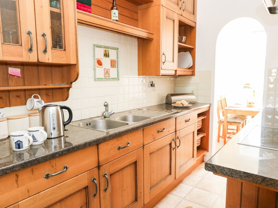 A kitchen with wooden cabinets and dining table at Flat 3, 4 Park Road in Swanage