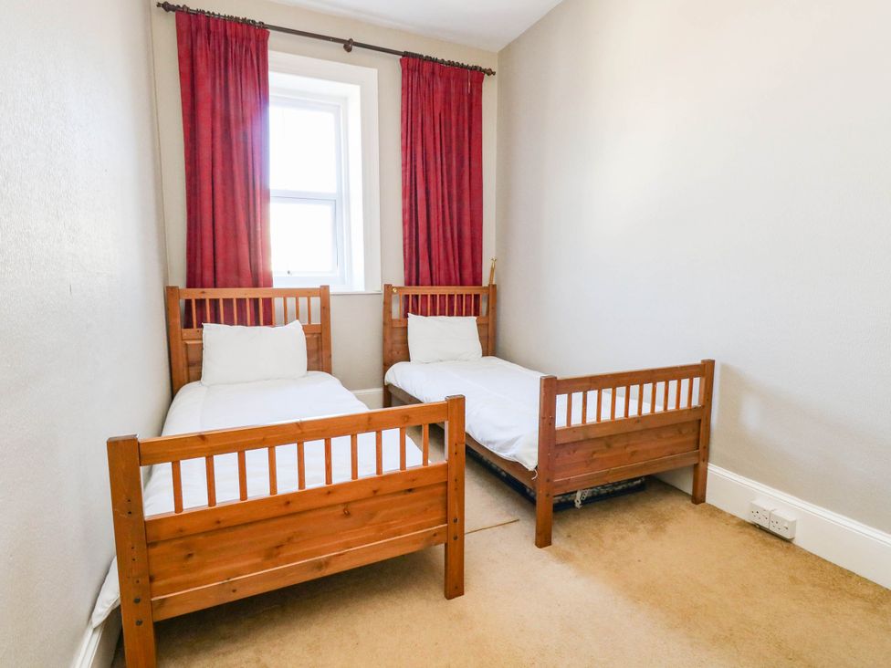 A bedroom with two single beds and red curtains at Flat 3, 4 Park Road in Swanage