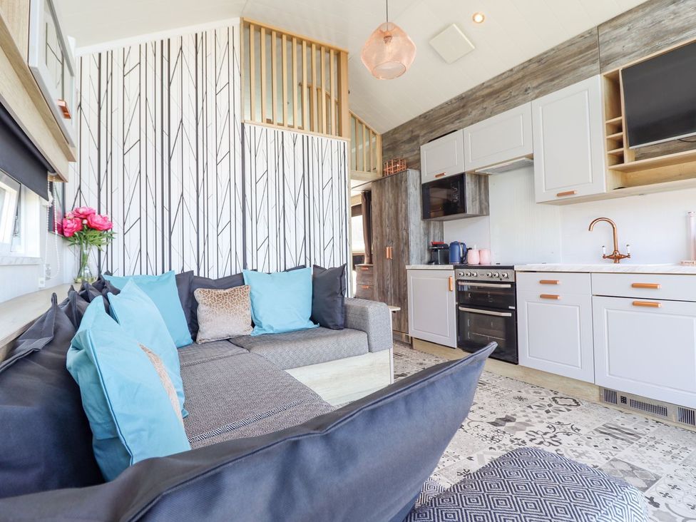 A living room with a couch and kitchen area at Posh Pod in Cemaes Bay