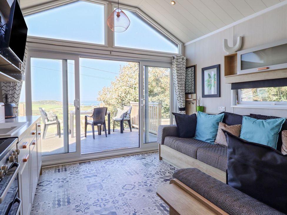 A living room with a sofa and sliding glass door at Posh Pod in Cemaes Bay