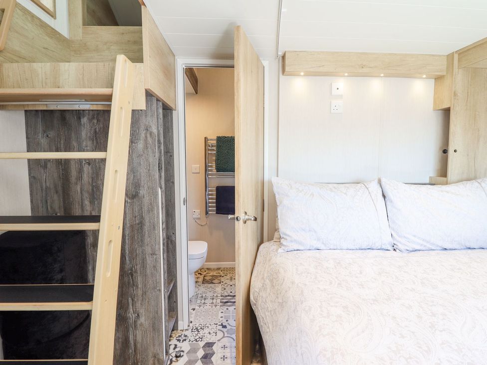 A bedroom with a bed and a bathroom door at Posh Pod in Cemaes Bay