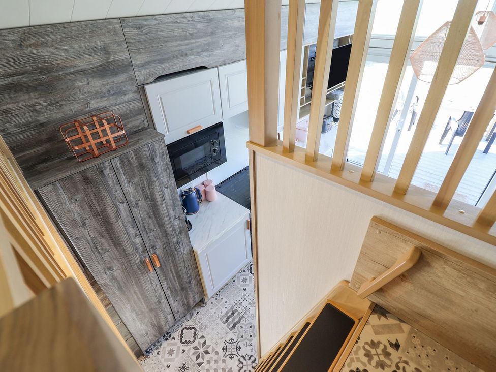 A kitchen with cabinets and a staircase at Posh Pod in Cemaes Bay
