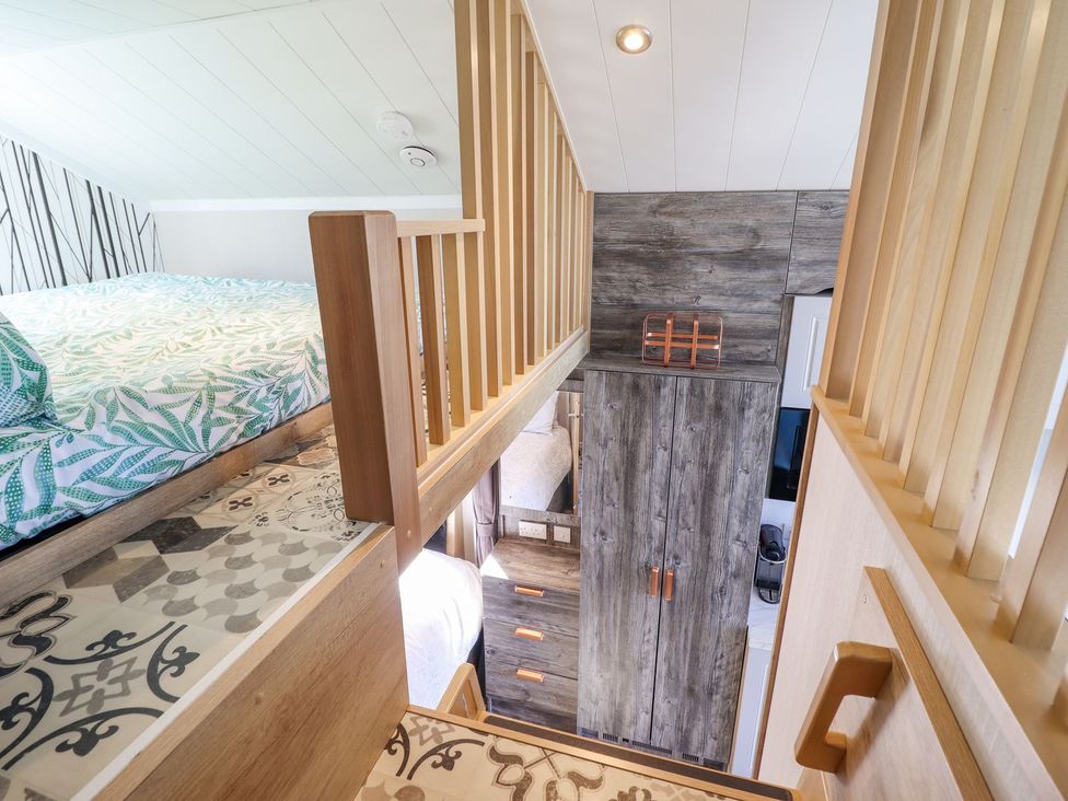 A bedroom with a bed and wardrobe at Posh Pod in Cemaes Bay