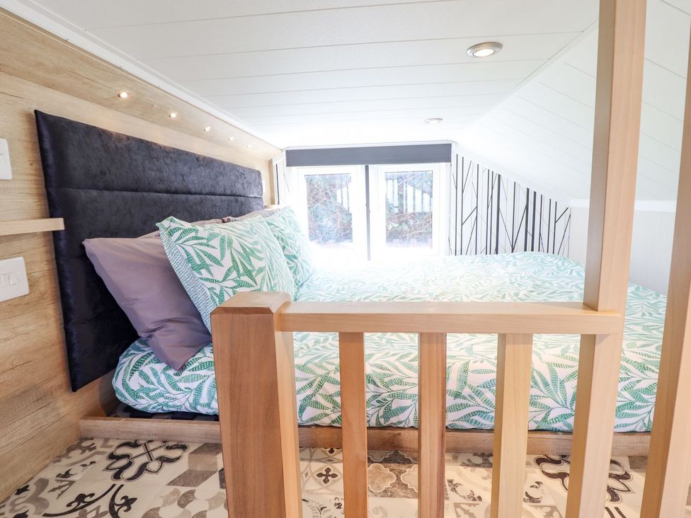 A bedroom with a bed and pillows at Posh Pod, Cemaes Bay