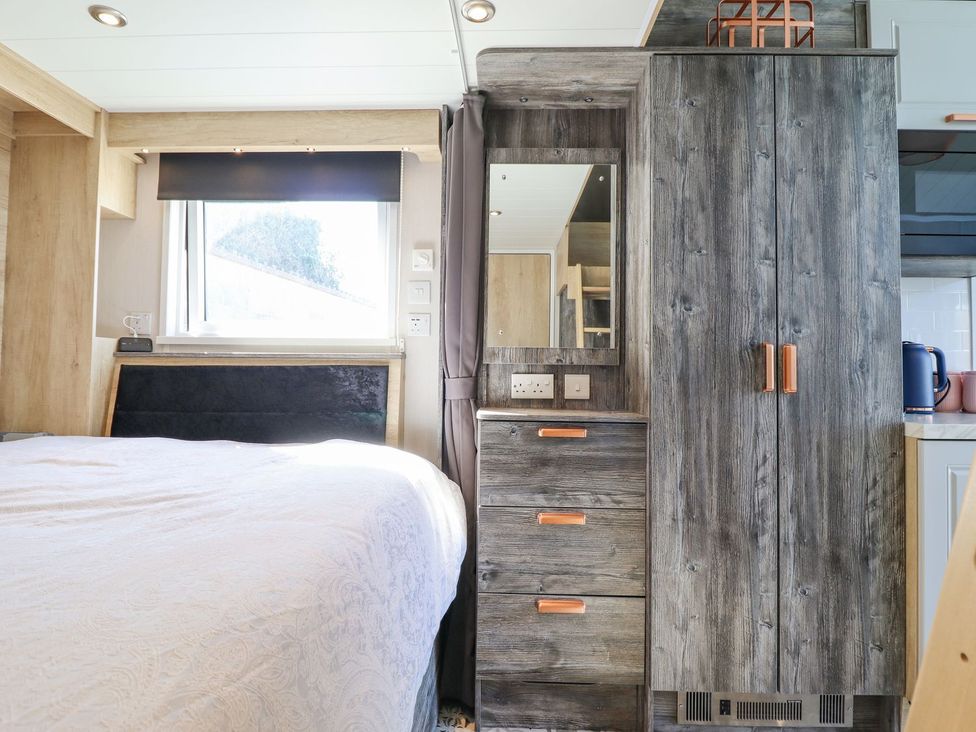 A bedroom with a bed and wardrobe at Posh Pod in Cemaes Bay