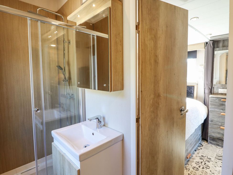 A bathroom with a shower and sink at Posh Pod in Cemaes Bay