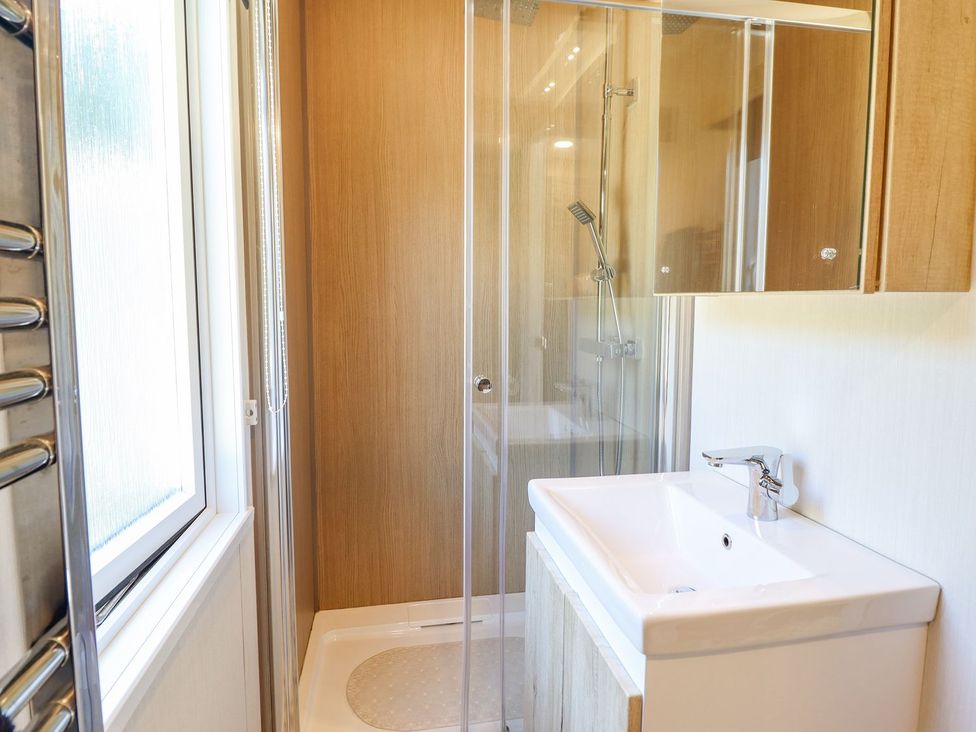 A bathroom with a shower and sink at Posh Pod in Cemaes Bay