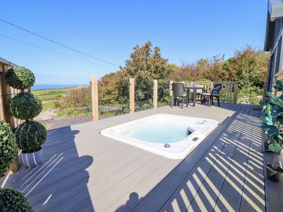 An outdoor area with a hot tub and seating at Posh Pod in Cemaes Bay