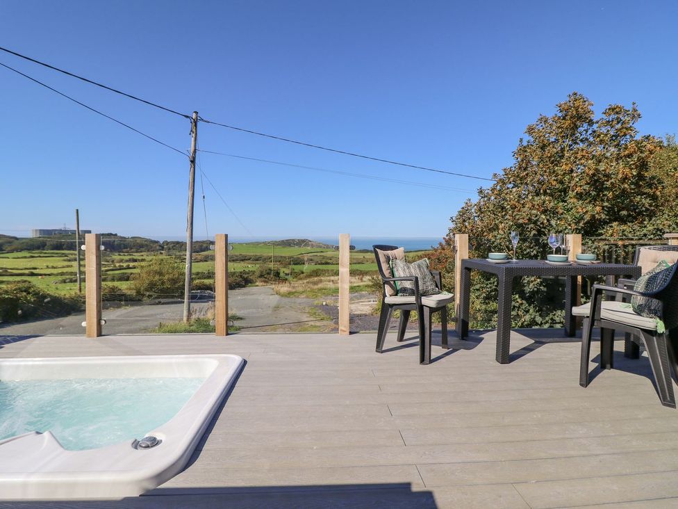 An outdoor area with a hot tub and dining table at Posh Pod in Cemaes Bay