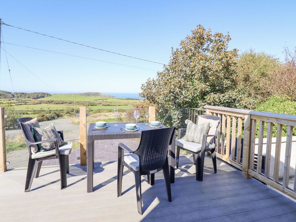 An outdoor deck with a table and chairs at Posh Pod in Cemaes Bay