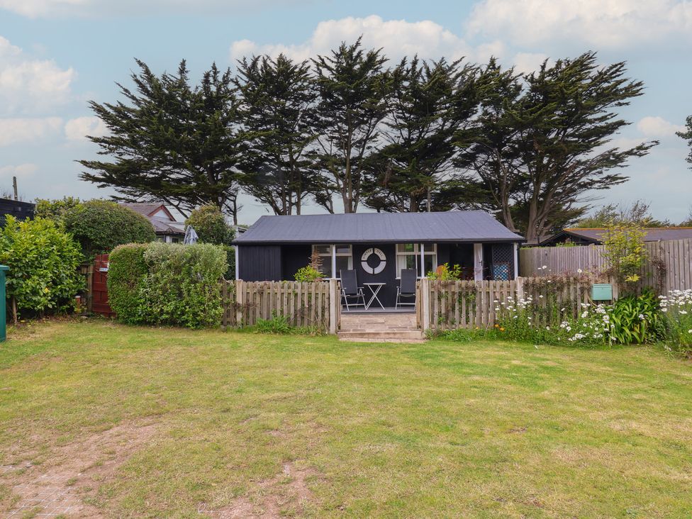 A garden with a building and chairs at Dingle Dell in Braunton