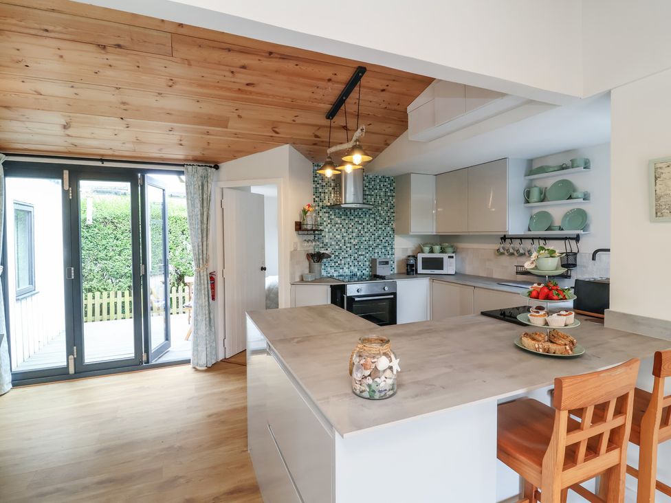 A kitchen with a counter and bar stools at Dingle Dell in Braunton