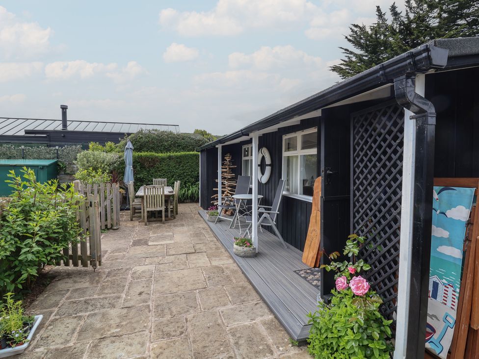 A garden area with a table and chairs near a house at Dingle Dell in Braunton