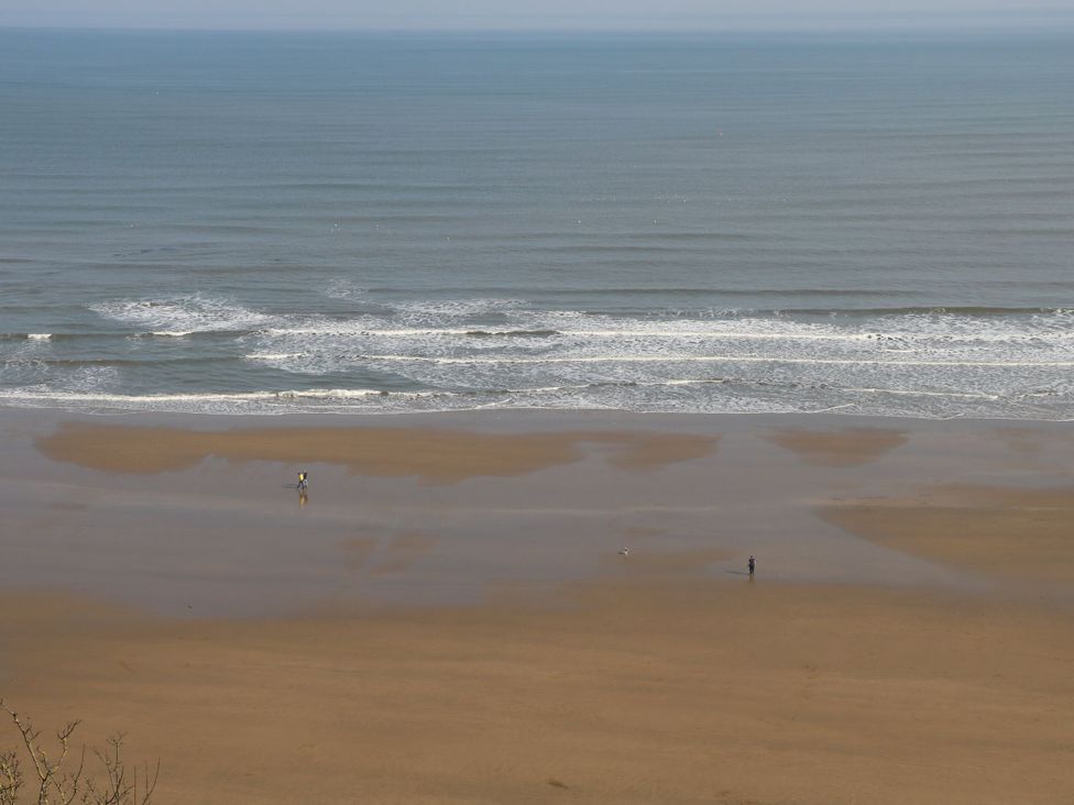 A beach with two people walking along the shore at Memory Maker in Bridlington
