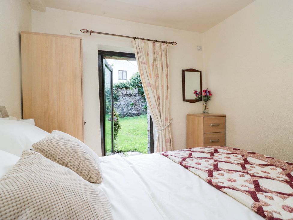 A bedroom with a bed and view to the garden at Rooftops in Lindale