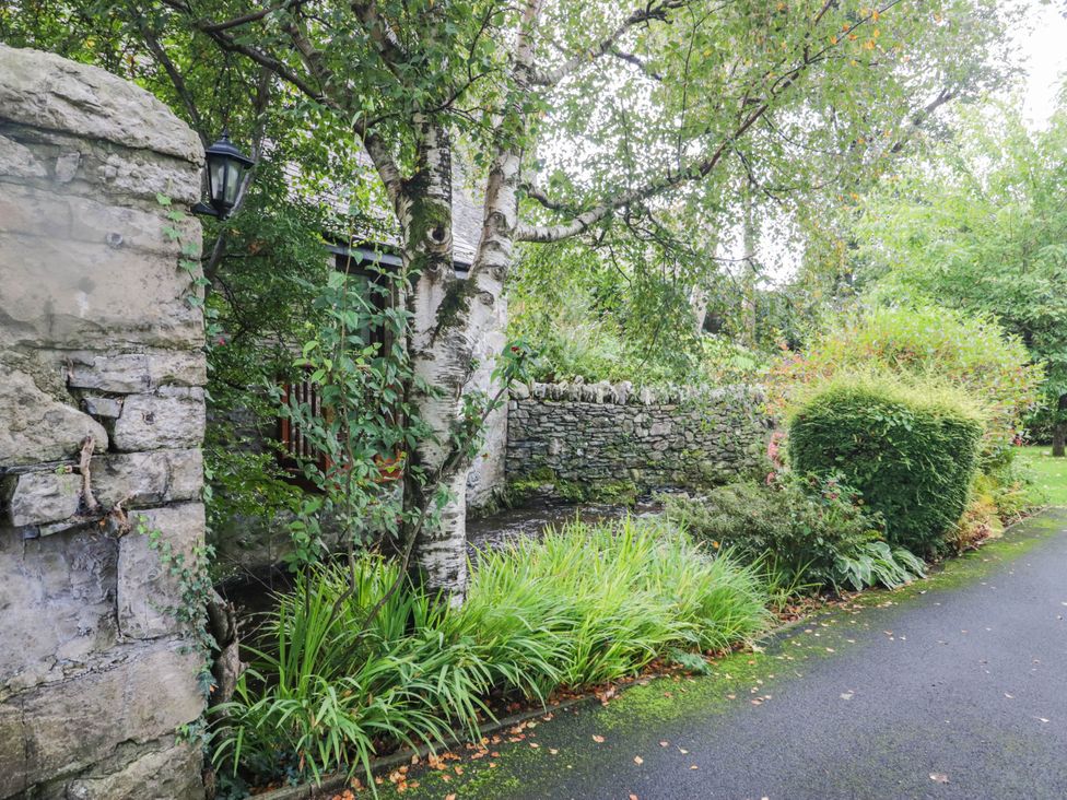 A garden with a stone wall and a path at Rooftops in Lindale