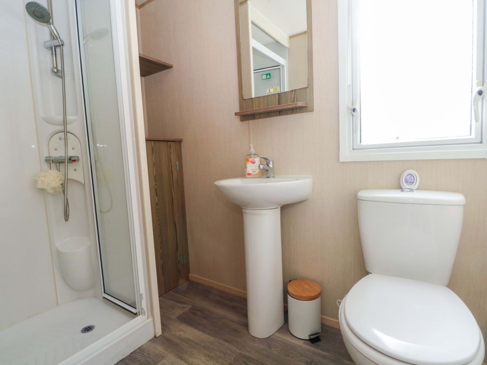 A bathroom with a shower, toilet, wash basin and mirror at Kensington 49