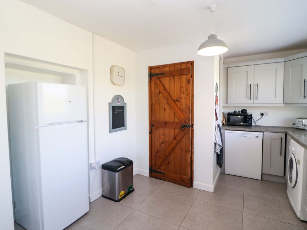 A kitchen with a refrigerator and wooden door at Tach Ferme