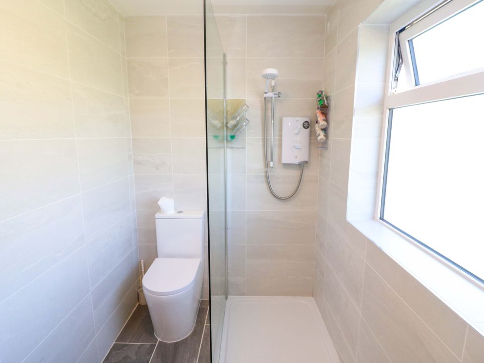 A bathroom with a shower, toilet and window at Tach Ferme