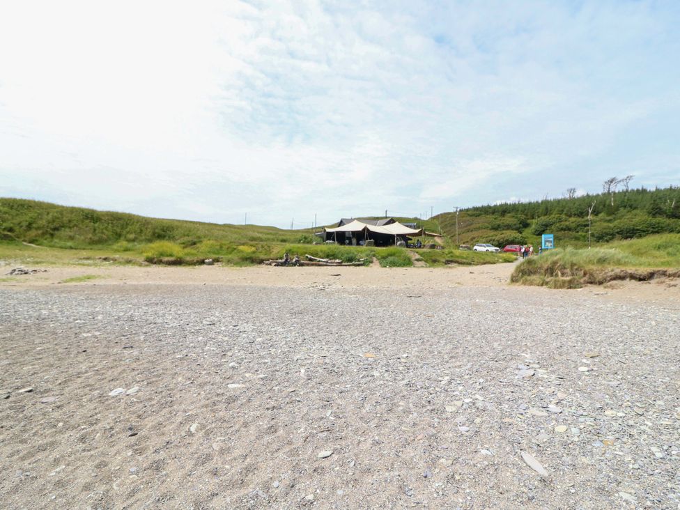 A beach with grass and a building in the background at Tach Ferme