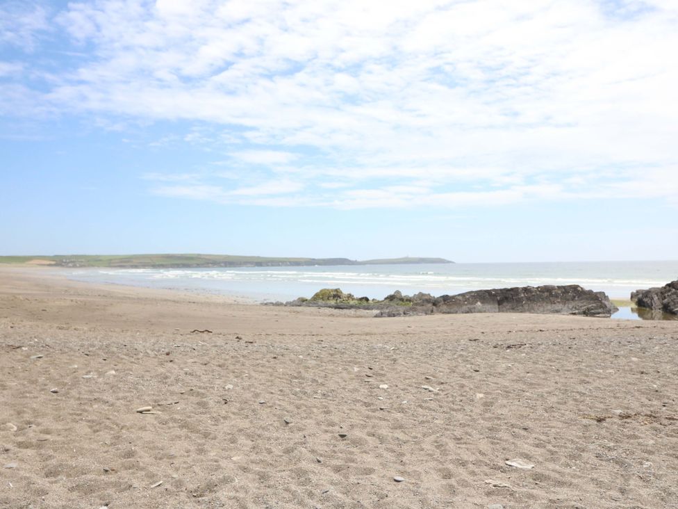 A beach with sand, water, and rocks at Tach Ferme in 