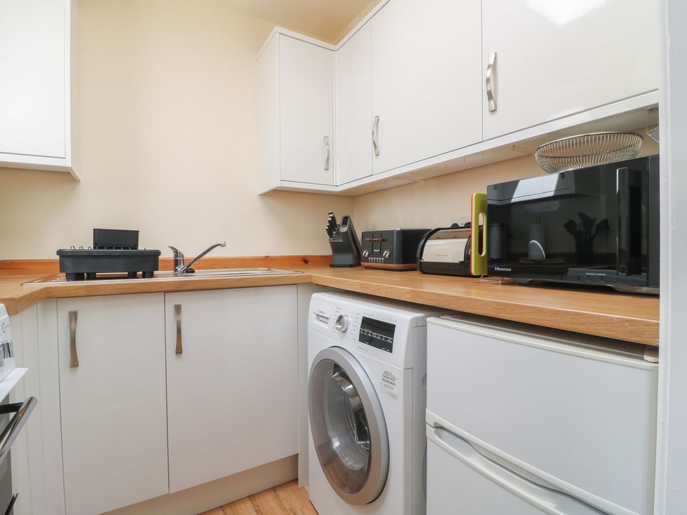 A kitchen with a washing machine and microwave at 27a Wolds Drive Nottingham