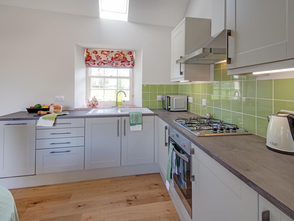 A kitchen with cabinets, sink, gas stove and microwave at Country Cottage Sleeps 3 with Garden and Parking