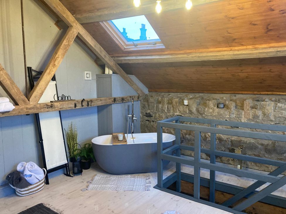 A bathroom featuring a bathtub and wooden beams at 1-Bed Barn Conversion, Sleeps 2 with Parking Niwbwrch (newborough)