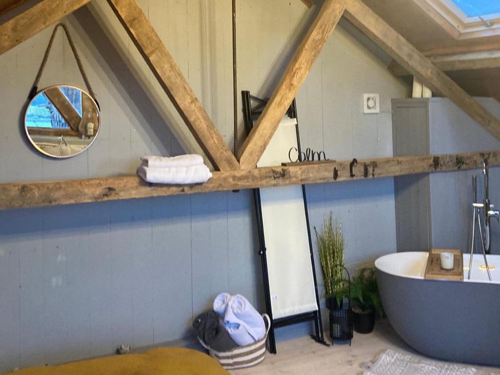 A bathroom with a bathtub and towels at 1-Bed Barn Conversion, Sleeps 2 with Parking, Niwbwrch (newborough)