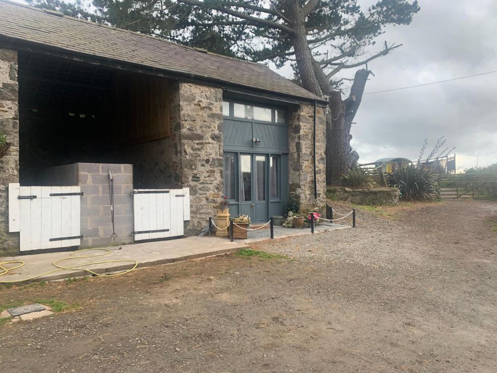 A barn exterior with stone walls and wooden doors at 1-Bed Barn Conversion, Sleeps 2 with Parking, Niwbwrch (newborough)