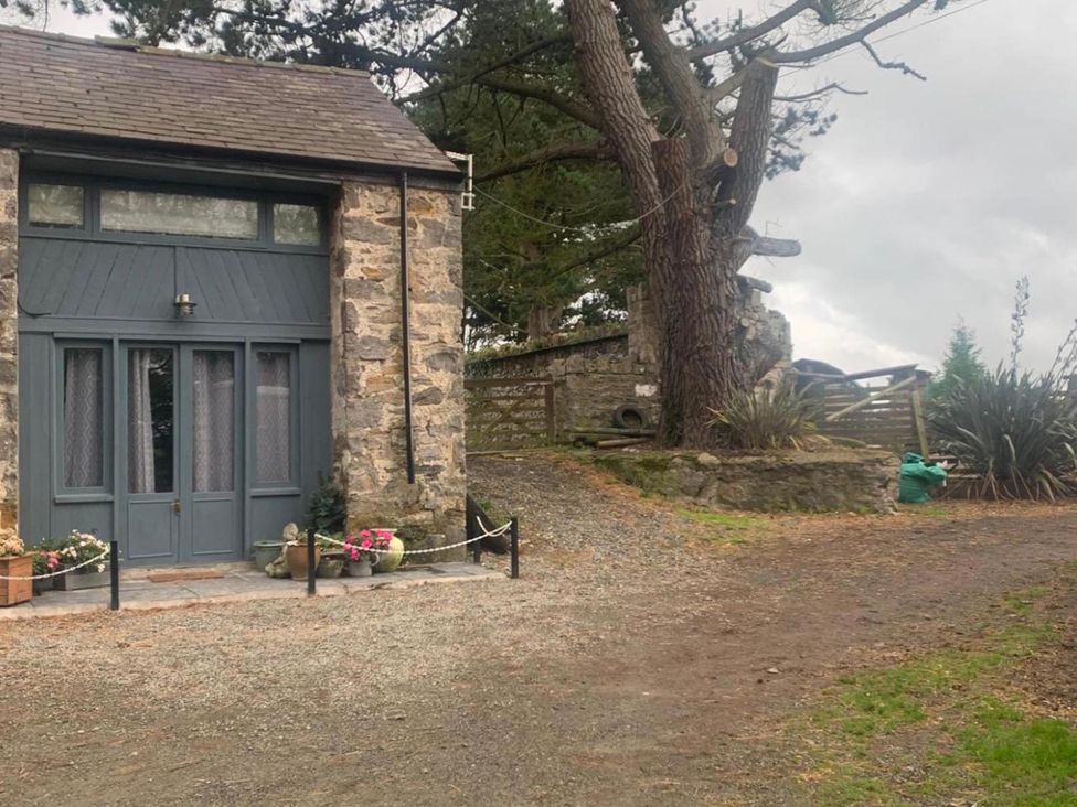 An outdoor view of a stone building with a door and windows at 1-Bed Barn Conversion, Sleeps 2 with Parking, Niwbwrch (newborough)