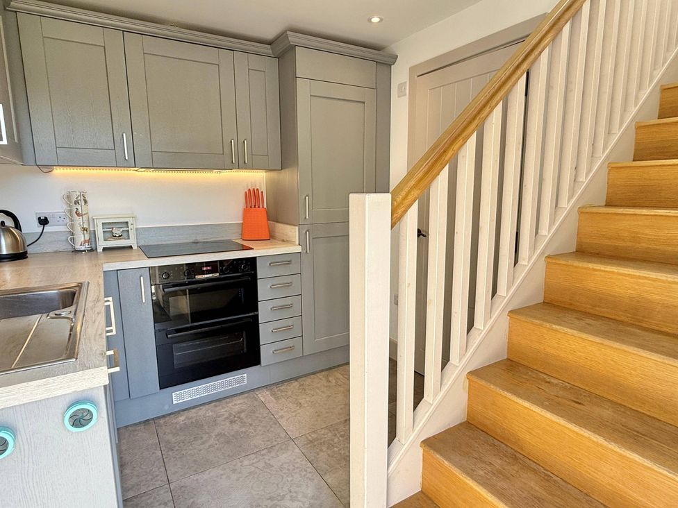 A kitchen with cabinets and a staircase at Charming Barn Annex with Stables New Forest Escape