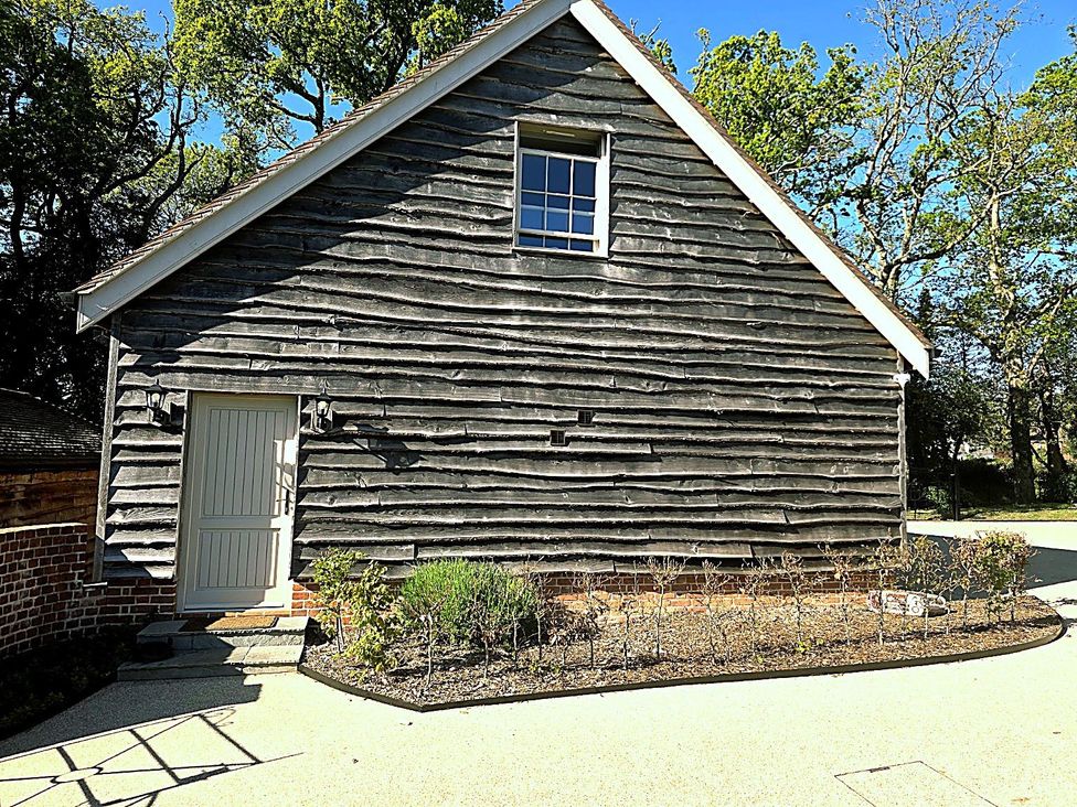 A wooden building with a door and window in the garden at Charming Barn Annex with Stables New Forest Escape