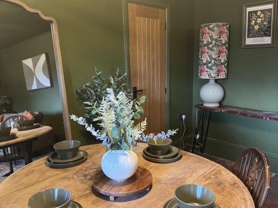 A dining room with a table set and a vase of foliage at Llysawelon 2-Bed Cottage, Sleeps 5, Pets Ok in Llysawelon near Llansteffan
