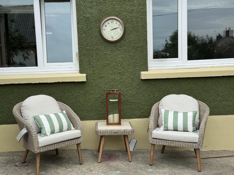 An outdoor seating area with two chairs, a table, and a clock at Llysawelon 2-Bed Cottage, Sleeps 5, Pets Ok near Llysawelon