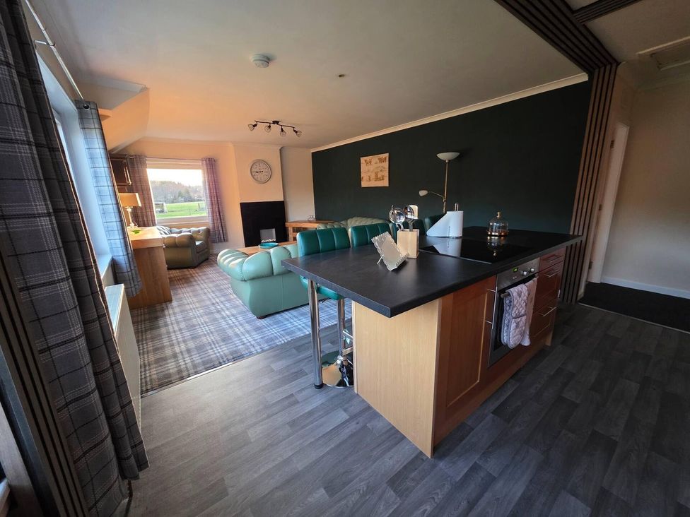 A kitchen island with stools near a living area at Highlands - River View - Apt - Sleeps 4 - Garden Garve near Strathpeffer